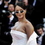 A celebrity on the red carpet wearing a stylish white dress and sunglasses