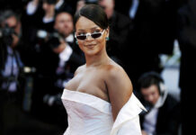 A celebrity on the red carpet wearing a stylish white dress and sunglasses