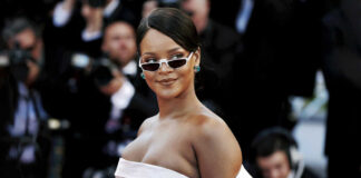 A celebrity on the red carpet wearing a stylish white dress and sunglasses