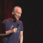 Man holding microphone on stage in dark setting