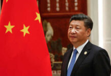 Man in suit standing next to Chinese flag