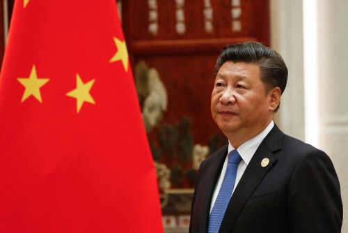 Man in suit standing next to Chinese flag