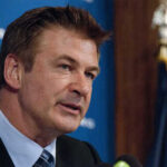 A man in a suit speaking at a press conference