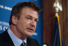 A man in a suit speaking at a press conference