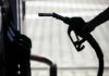 Silhouette of a hand holding a fuel nozzle at a gas station