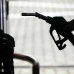 Silhouette of a hand holding a fuel nozzle at a gas station