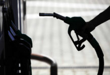 Gasoline SHOCKWAVE – Iran Conflict Hits U.S. Wallets Silhouette of a hand holding a fuel nozzle at a gas station