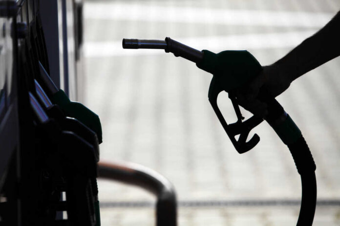 Silhouette of a hand holding a fuel nozzle at a gas station