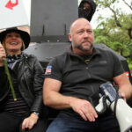 Two individuals at a protest, one holding a sign and the other with a megaphone
