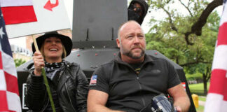 Two individuals at a protest, one holding a sign and the other with a megaphone