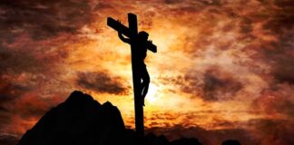 Silhouette of a crucifix against a dramatic sunset sky