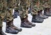 Row of soldiers in camouflage uniforms standing at attention with military boots