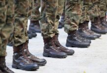 Row of soldiers in camouflage uniforms standing at attention with military boots