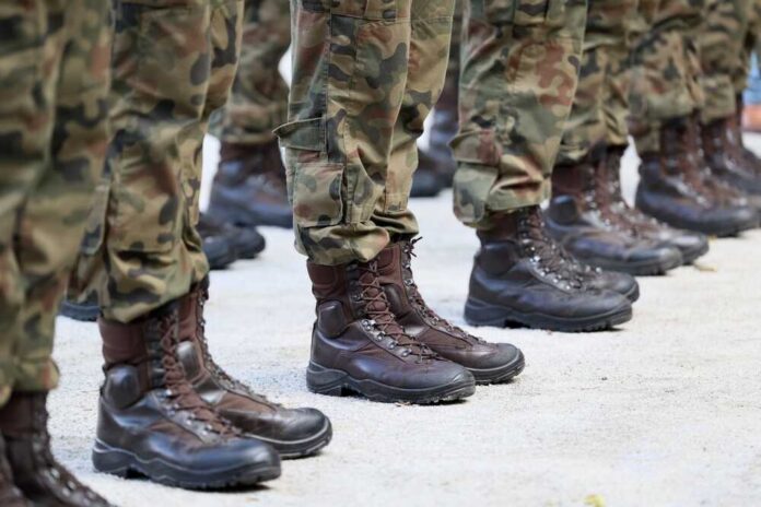 Row of soldiers in camouflage uniforms standing at attention with military boots