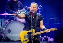 A musician passionately performing on stage with a guitar