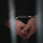 Killer’s Chilling Boast Caught on Camera Close-up of handcuffed hands behind bars