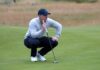 Golf Shock: McIlroy’s Lead Evaporates Golfer crouching on the green, preparing to putt