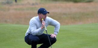 Golfer crouching on the green, preparing to putt