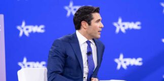 A man in a blue suit speaking at a conference