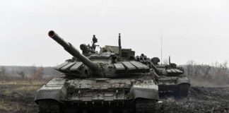 Two military tanks positioned in a muddy field