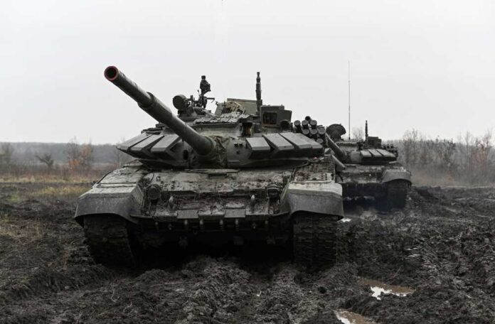 Two military tanks positioned in a muddy field