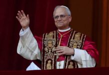 Religious leader in ceremonial attire waving from a balcony
