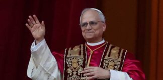 Religious leader in ceremonial attire waving from a balcony