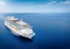 A large cruise ship sailing on a calm ocean under a clear blue sky