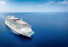 A large cruise ship sailing on a calm ocean under a clear blue sky