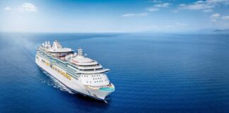 A large cruise ship sailing on a calm ocean under a clear blue sky