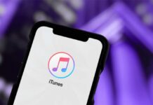 AI “Singer” Dominates Top Charts—Is It Real? Close-up of a smartphone displaying the iTunes app logo