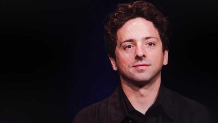 A man with curly hair smiling against a dark background