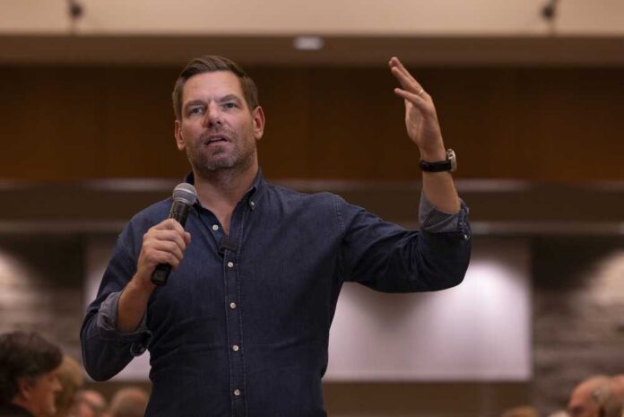 A speaker gesturing while holding a microphone during a presentation