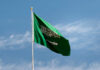 Saudi Arabian flag waving against a blue sky