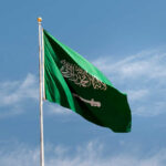Saudi Arabian flag waving against a blue sky