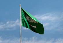 Saudi Arabian flag waving against a blue sky