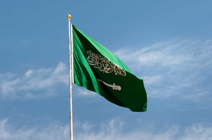 Saudi Arabian flag waving against a blue sky