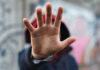 A close-up of a hand held up in front of a person against a graffiti background