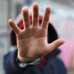 A close-up of a hand held up in front of a person against a graffiti background