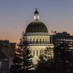 Illuminated dome of a government building against a sunset sky