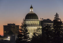 Illuminated dome of a government building against a sunset sky