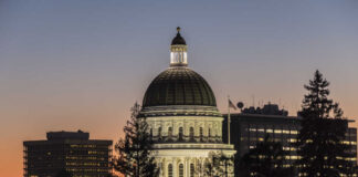 Illuminated dome of a government building against a sunset sky