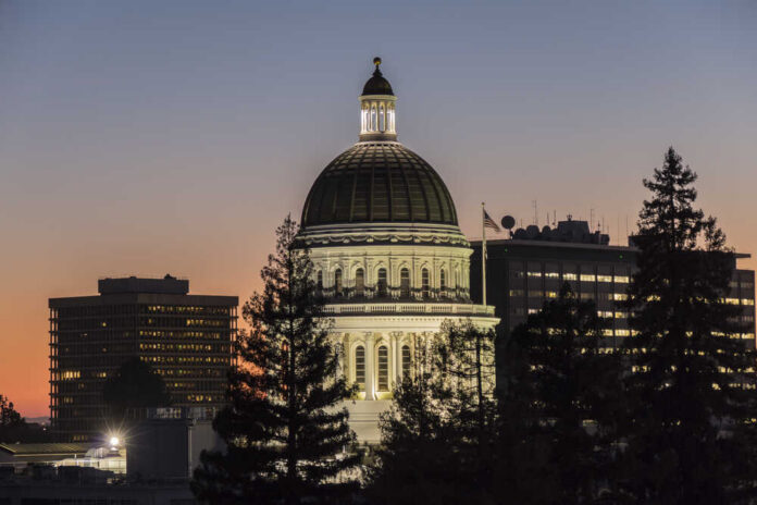 Illuminated dome of a government building against a sunset sky