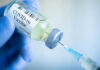 Ebola Vaccine Trial: COVID Controversy Repeats? Gloved hand holding COVID19 vaccine vial and syringe