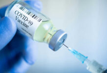 Gloved hand holding COVID19 vaccine vial and syringe