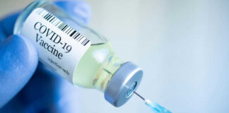 Gloved hand holding COVID19 vaccine vial and syringe