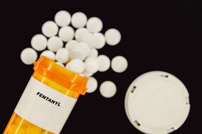 Prescription bottle of fentanyl tablets scattered on surface