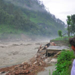 Flooded Cave Breakthrough Changes Everything Men observe flood-damaged riverside buildings and debris