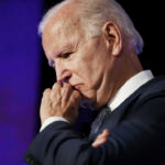 elderly man in suit resting chin on hand in thought
