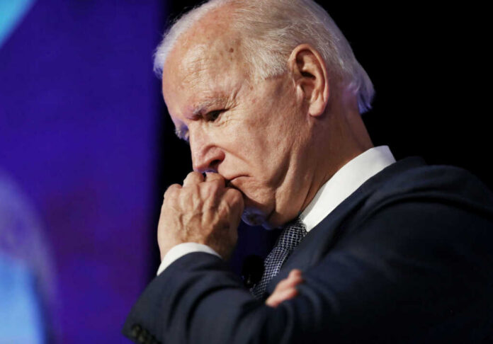 elderly man in suit resting chin on hand in thought